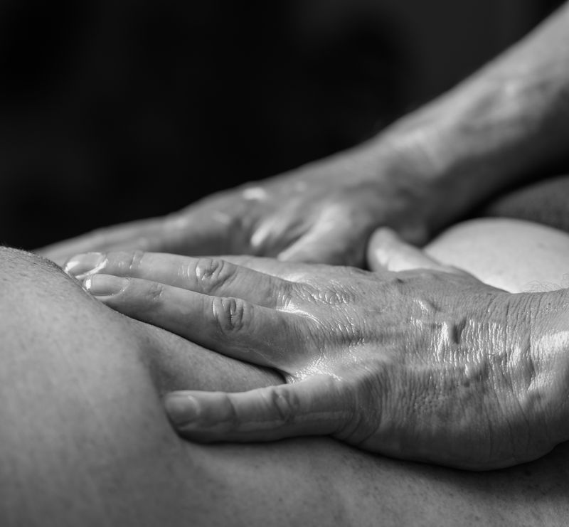 Zwart-witfoto van de handen van de therapeut tijdens een massage